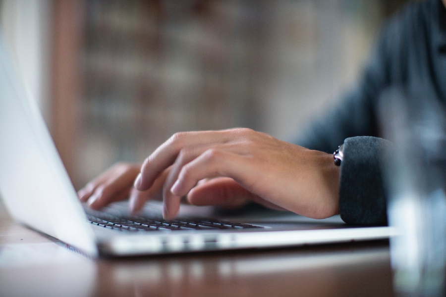 Hands typing on a laptop keyboard.