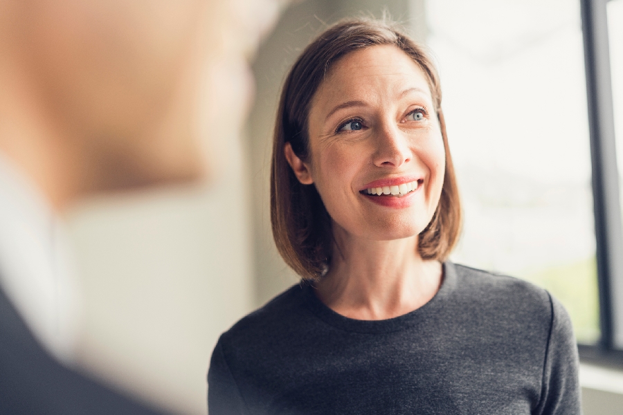 A woman in a black shirt smiling and listening