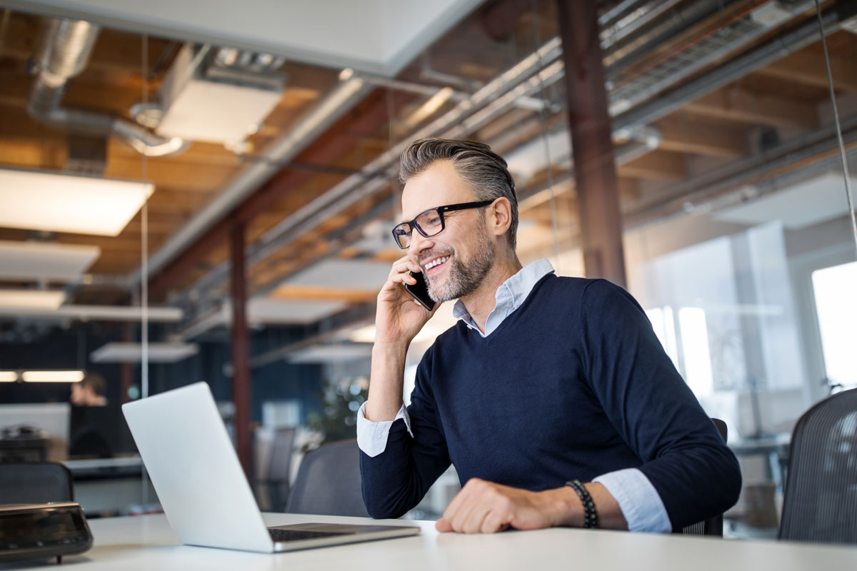 A man on a phone and working with a laptop